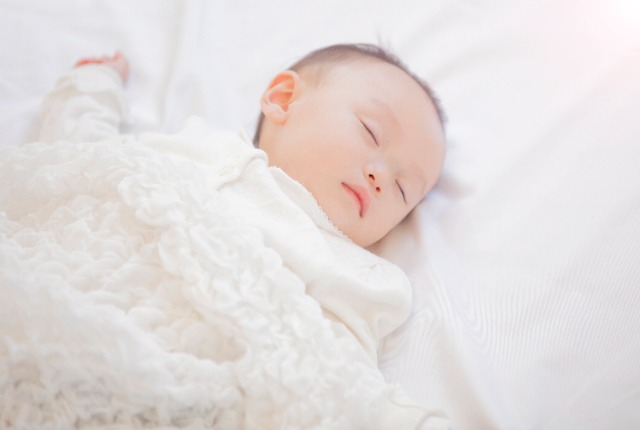 頭を抱えベッド脇で悩む男性